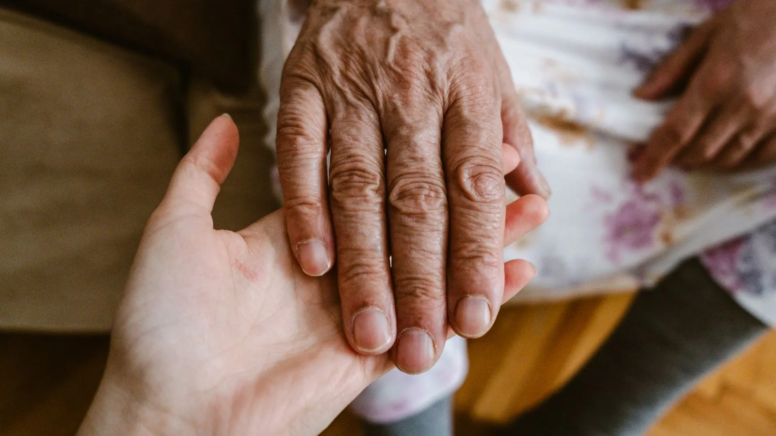 La mano de una hija sostiene la de su madre mayor al volver a casa tras el alta