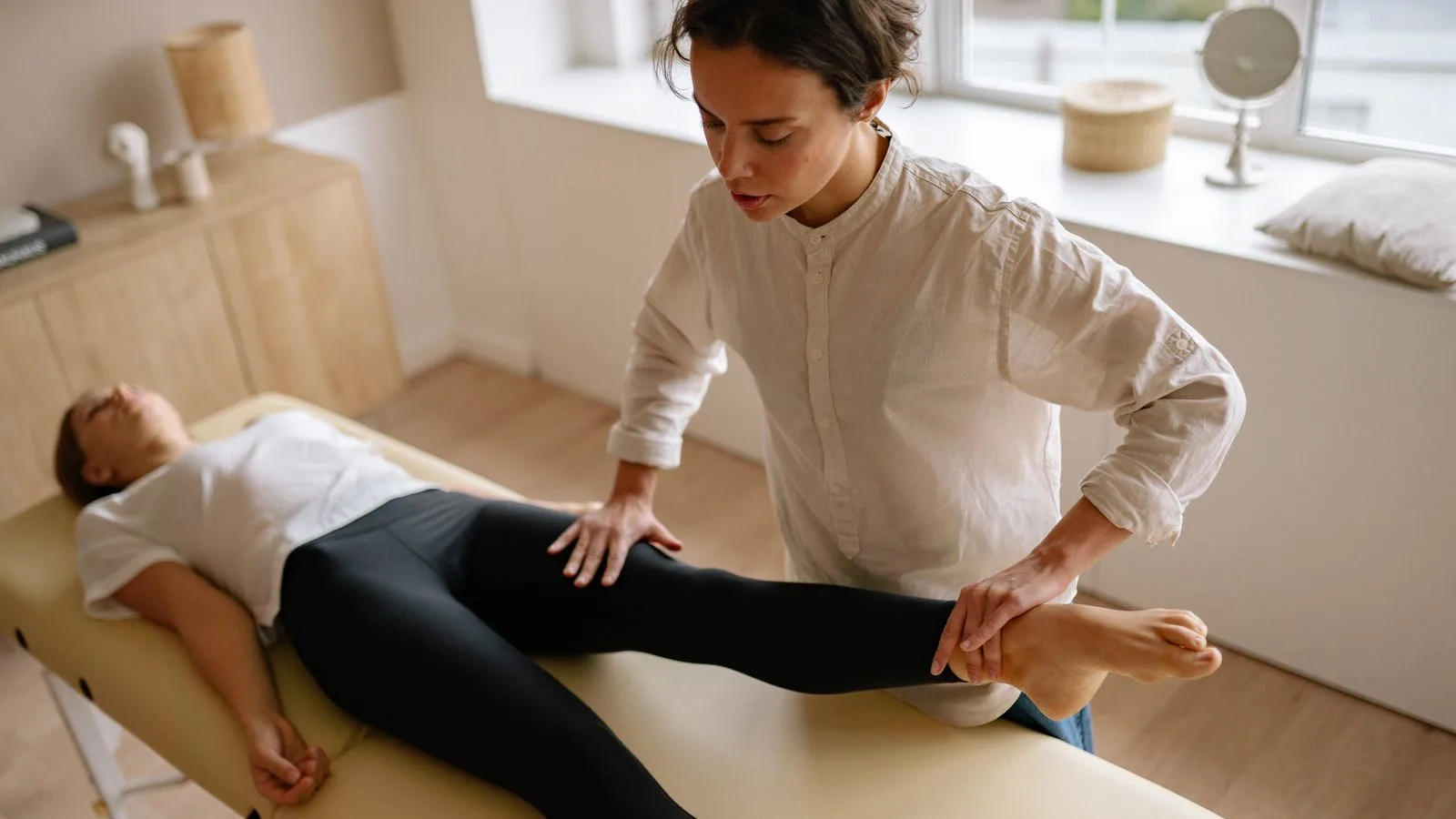Profesional aplicando terapia manual en la pierna de una paciente