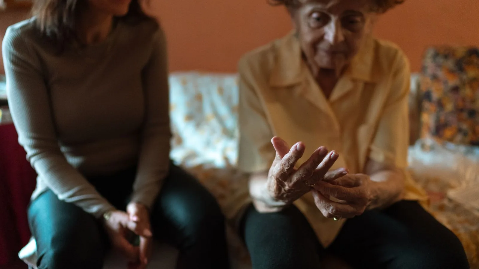 Cuidadora escuchando a una mujer mayor sentadas juntas en el sofá