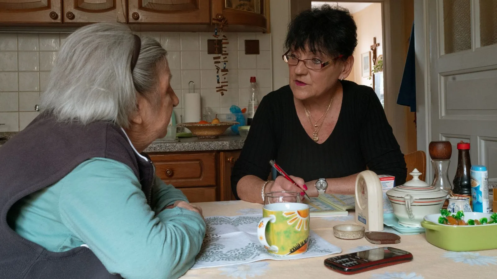 Terapeuta ocupacional durante una visita a domicilio con una mujer mayor en su cocina