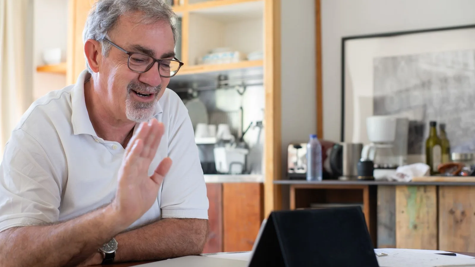 Hombre mayor en una sesión de terapia ocupacional online desde la cocina de su casa