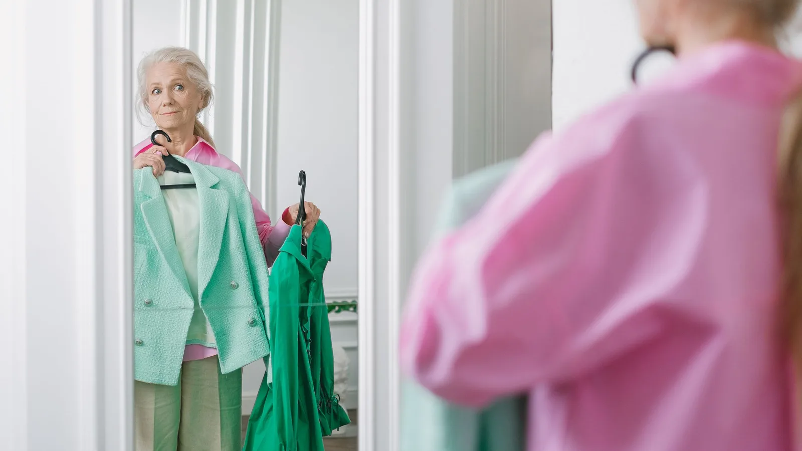 Mujer mayor eligiendo ropa frente al espejo de su dormitorio